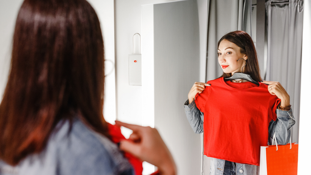 Соблазнительная рыжая девушка примеряет одежду перед зеркалом