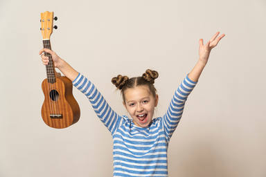 Teen,Girl,Holding,A,Guitar,Ukulele,And,Laughing,On,A