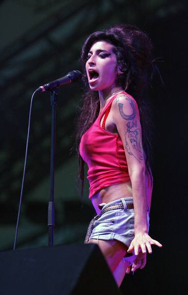 Amy Winehouse con shorts y camiseta de tirante, uno de sus estilismos más recurrentes sobre el escenario